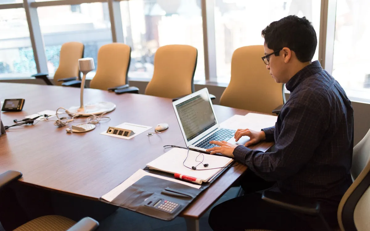 Employee working on a MacBook at a conference room table in a bright office