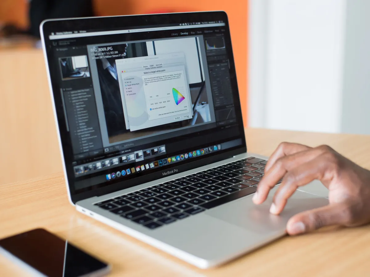 Close-up of a hand on the trackpad of a MacBook Pro on an office desk